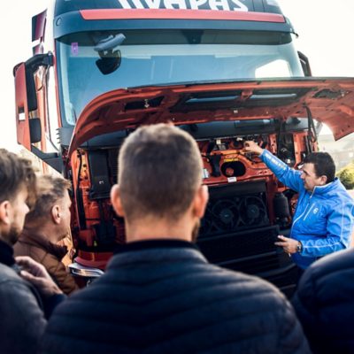 The driver trainer and several Vapas drivers stand around a truck for a training session