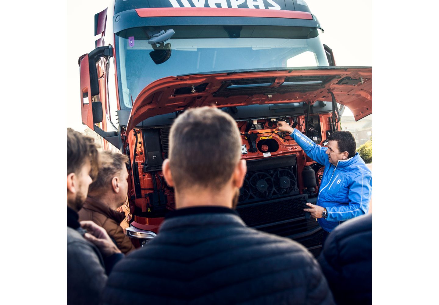 El instructor de conductores y varios conductores de Vapas de pie alrededor de un camión, para una sesión de capacitación