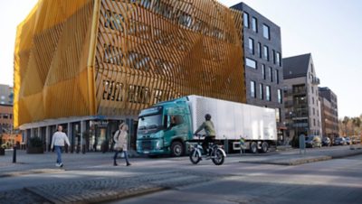 People walking and cycling in front of a Volvo FM Electric truck