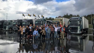 A Volvo Group team standing in front of seven Volvo trucks in Sweden