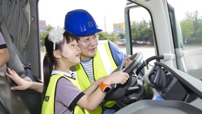 A man and child sitting in the driver seat of a truck