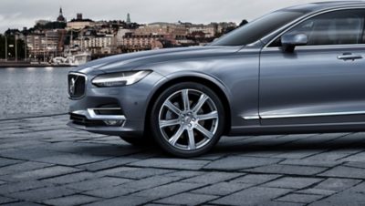 A grey Volvo car parked on a street by the water