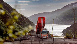 Red Volvo autonmous Volvo FH truck unloading limestone at quarry in Norway