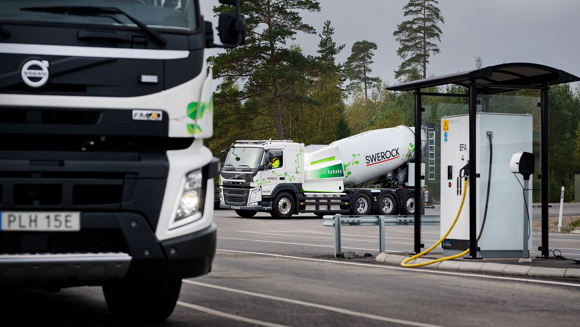 Volvo FMX och FM parkerade nära en laddningsstation