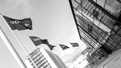 Five blue Volvo flags in front of a Volvo Group building