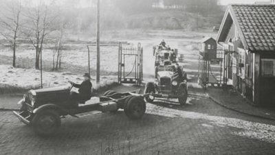 A line of old Volvo trucks driving through a gate