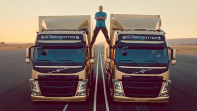 Jean Claude Van Damme stojący w rozkroku między dwoma samochodami ciężarowymi Volvo I Volvo Group