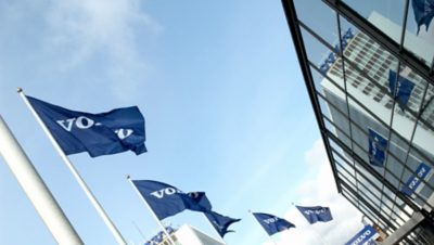 Five blue Volvo flags in front of a Volvo Group building