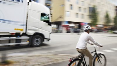 A man riding a cycle along with bus I Volvo Group