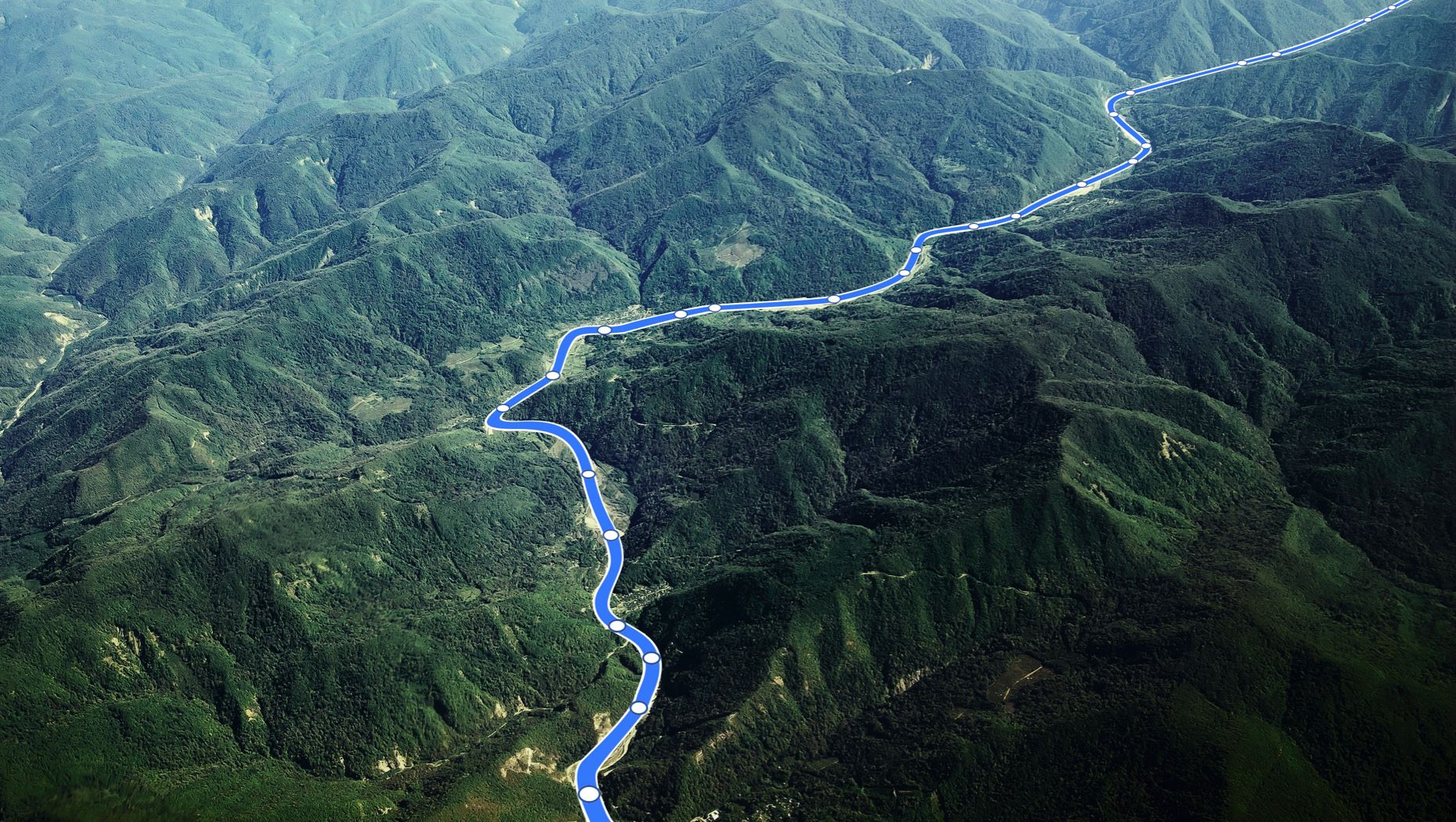 Uma estrada serpenteia um vale numa paisagem montanhosa. Sobreposição de gráficos.