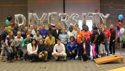 Employees with nine balloons behind them spelling DIVERSITY