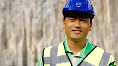 Volvo Group worker at a construction site wearing a blue helmet and a yellow safety west