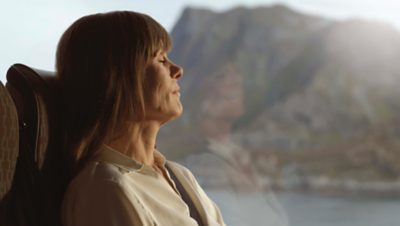 Close up of woman resting in her coach seat, mountains in the background