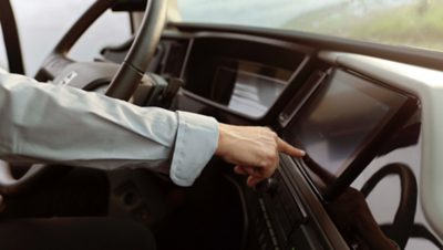 Hand wijzend naar een scherm in de chauffeursomgeving van een coach