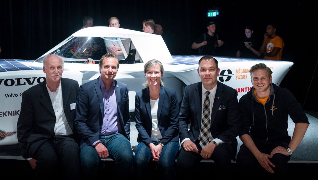 5 persons sitting in front of the vehicle