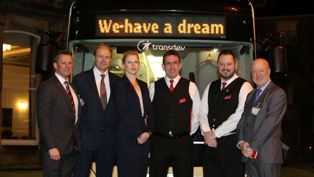Six persons in front of a Volvo bus