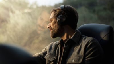Miespuolinen matkustaja katselee kuulokkeet korvilla ulos ikkunasta
