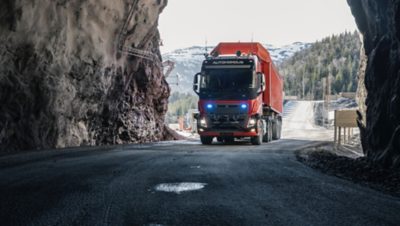  Self-driving truck with high beams turned on, running down a road in a dark mine
