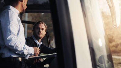 Dos conductores de autobús conversando en un autobús estacionado