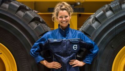 A woman posing in front of Volvo construction vehicle