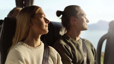 Tři cestující na svých sedadlech se dívají z okna