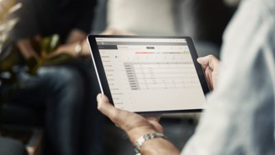 Una imagen de manos sosteniendo una tablet con la interfaz de Volvo Connect
