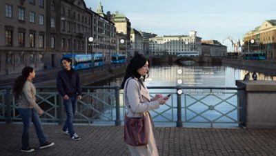 Woman crossing a bridge over a city canal. Two pedestrians in the periphery. Graphics overlay the photo.