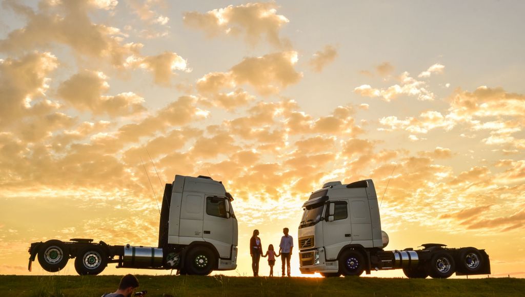 Casal com a minha no meio de dois caminhões Volvo