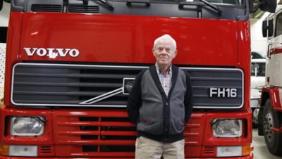 Bărbat în picioare în fața unui autocamion Volvo FH