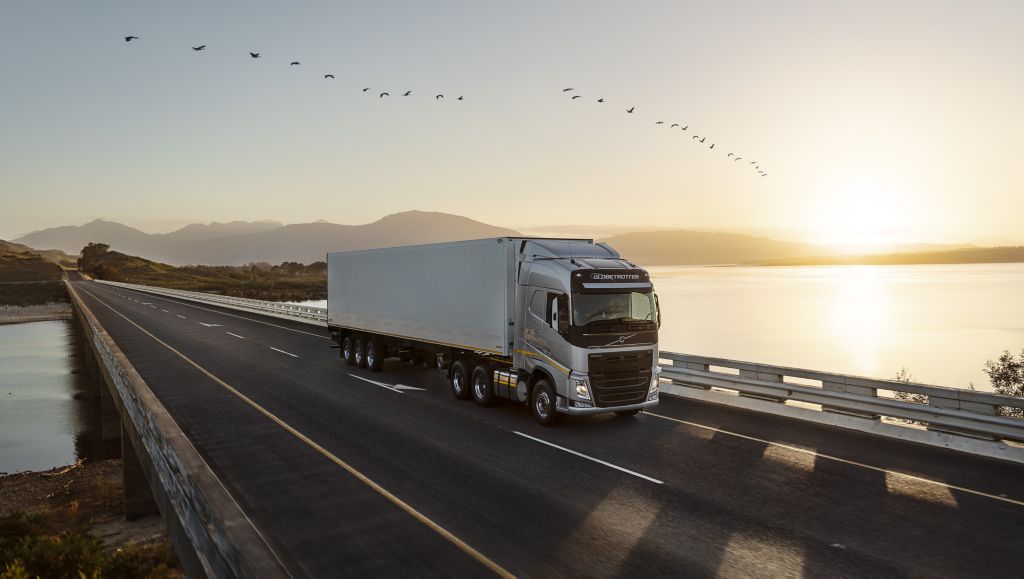 A Volvo truck driving by a lake as sun sets
