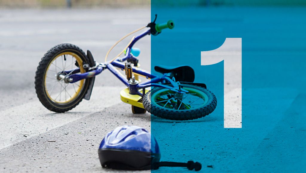 A child's bicycle and helmet lie on a road