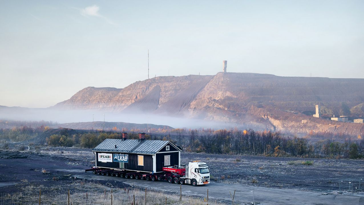 Een Volvo FH-truck transporteert een gebouw in Kiruna, Noord-Zweden, omgeven door mist