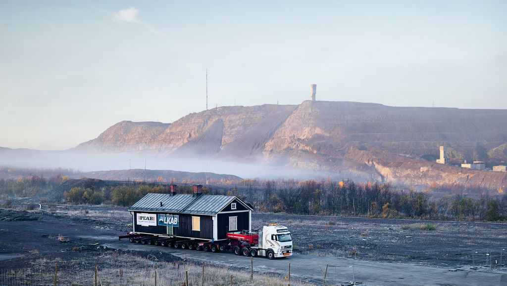 En Volvo FH-lastebil transporterer en bygning i Kiruna i Nord-Sverige, omgitt av tåke