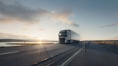 Un Volvo FH circulando junto a un río al atardecer