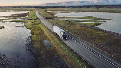 Un Volvo FH con I-Save conduce a través de un puente sobre un lago