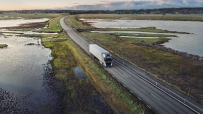 A Volvo FH with I-Save drives across a bridge over a lake