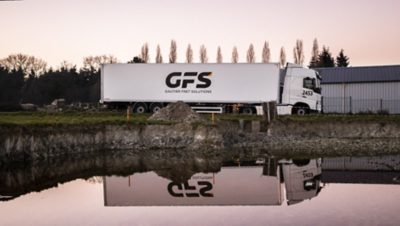 The Volvo FH with I-Save passes a lake and is reflected in the water