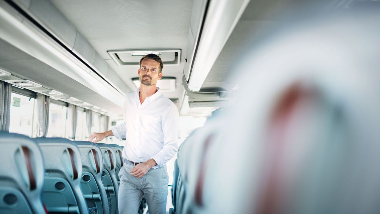 Karl Johansson walks along the aisle inside a Volvo coach