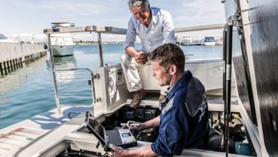 Volvo Penta worker diagnosing a boat with a computer while the boat owner looks on