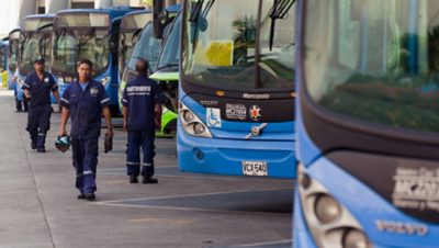 Volvo Group service workers in front of a line of blue Volvo buses