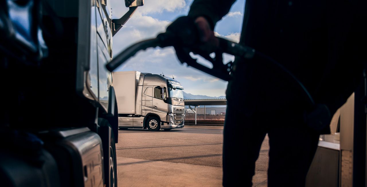Üzemanyagot tankoló ember, aki közben egy másik teherautót néz