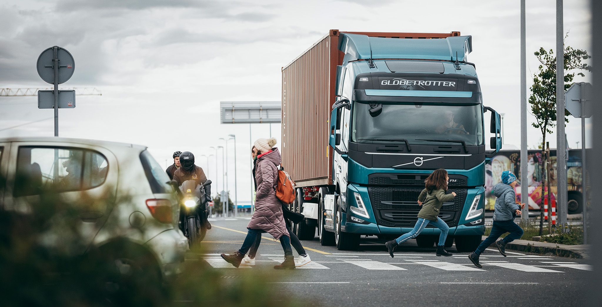 Persoane traversând prin fața unui autocamion staționar