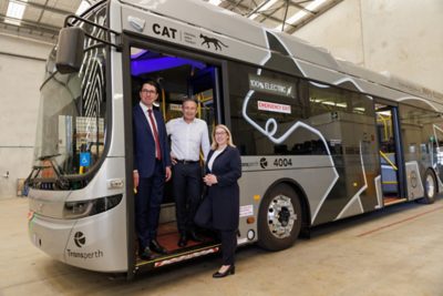 Western Australian ministers Patrick Gorman, Roger Cook and Rita Saffioti standing at the entrance to a gray and black new Volvo BZL Electric bus.