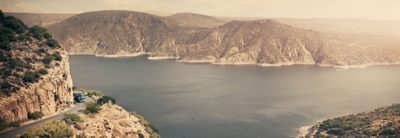 Vista panorámica de un lago en México con un autobús conduciendo por un camino de montaña