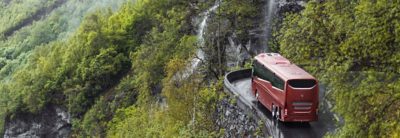 Vista da traseira do autocarro numa estrada de montanha com queda de água ao fundo