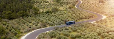 Autobús por una carretera serpenteante en un paisaje mediterráneo