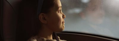 Dziewczyna z pasem bezpieczeństwa wygląda przez okno autobusu