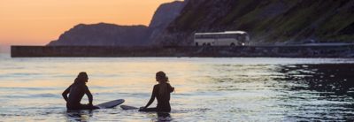 Deux surfeurs dans la mer au coucher du soleil