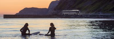 Two surfers in the sea during sunset