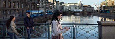 Woman crossing a bridge over a city canal. Two pedestrians in the periphery. Graphics overlay the photo